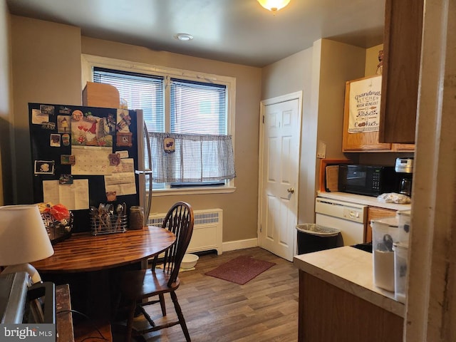 dining room featuring baseboards, radiator heating unit, and wood finished floors