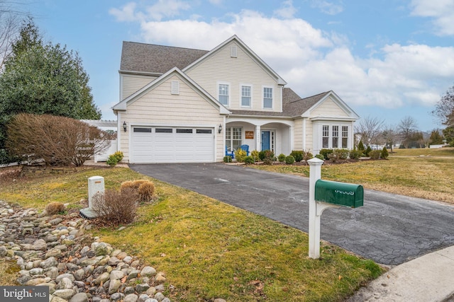 traditional-style house featuring a front yard, driveway, and an attached garage