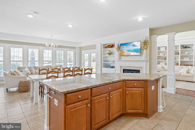 kitchen with built in shelves, light stone counters, a breakfast bar area, open floor plan, and light tile patterned flooring