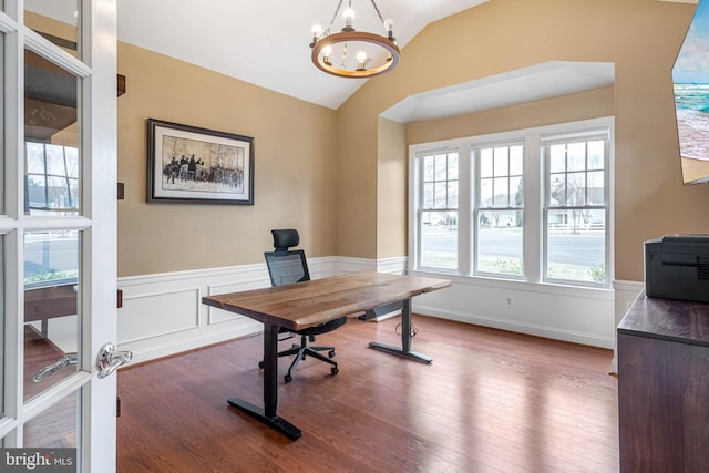 office space with wainscoting, a notable chandelier, vaulted ceiling, and wood finished floors