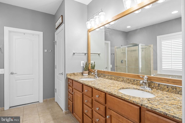 full bathroom featuring double vanity, tile patterned flooring, a shower stall, and a sink