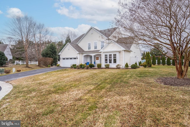 view of front of house featuring a front lawn, driveway, fence, a shingled roof, and a garage