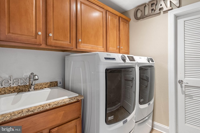 washroom featuring washer and dryer, cabinet space, a sink, and baseboards