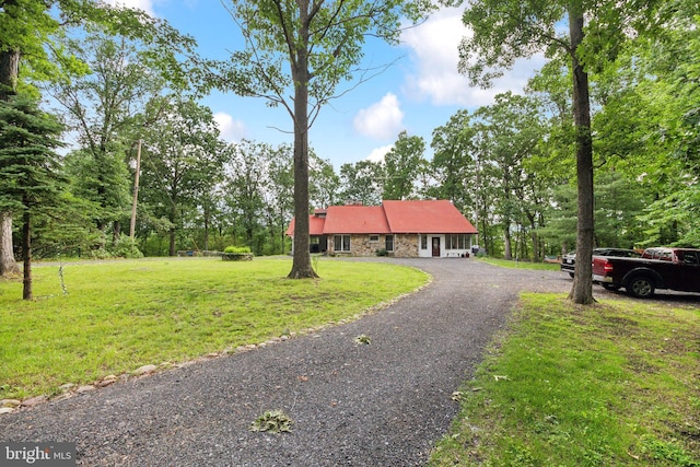 view of front of home with stone siding, aphalt driveway, and a front lawn