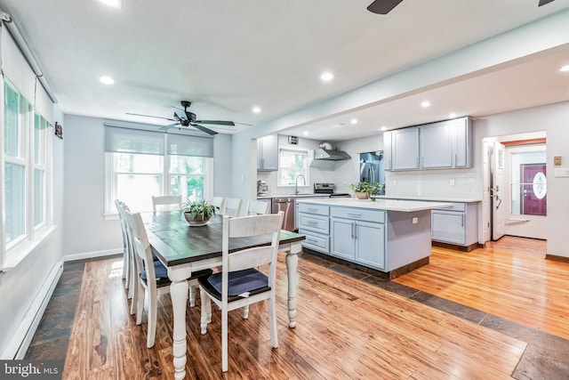 dining area with baseboards, baseboard heating, light wood-type flooring, and recessed lighting