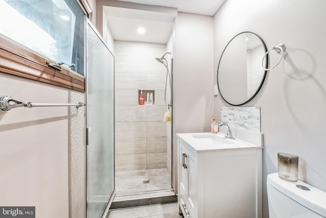 bathroom featuring toilet, a shower stall, and vanity