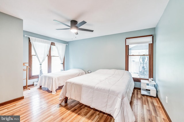 bedroom featuring light wood-type flooring, a ceiling fan, and baseboards