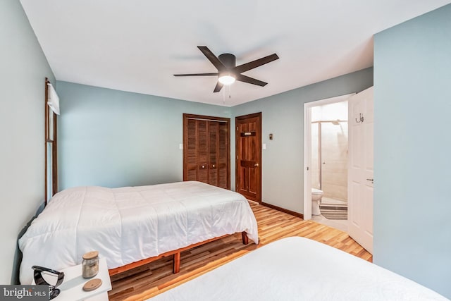 bedroom featuring baseboards, a ceiling fan, wood finished floors, ensuite bathroom, and a closet