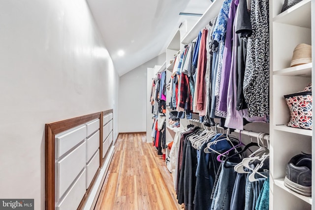 walk in closet with light wood-type flooring and vaulted ceiling