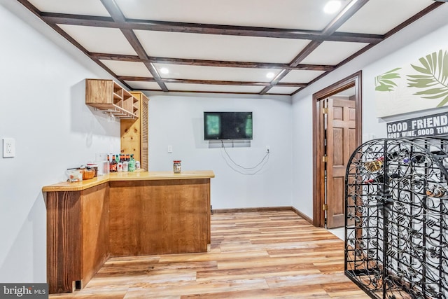 bar with a bar, light wood-style flooring, baseboards, and coffered ceiling