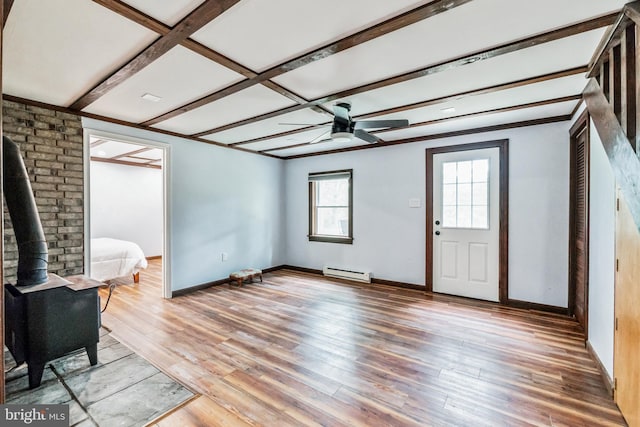 interior space with baseboards, light wood-style flooring, ceiling fan, a wood stove, and a baseboard heating unit