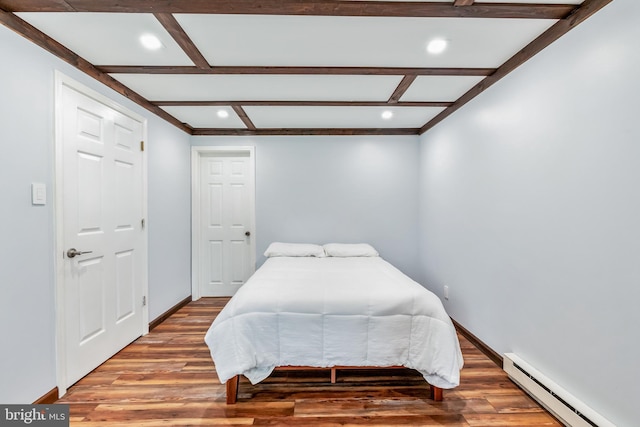 bedroom featuring a baseboard heating unit, wood finished floors, beam ceiling, and baseboards