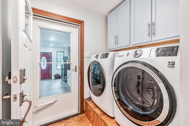 laundry room featuring light wood-style floors, cabinet space, and independent washer and dryer