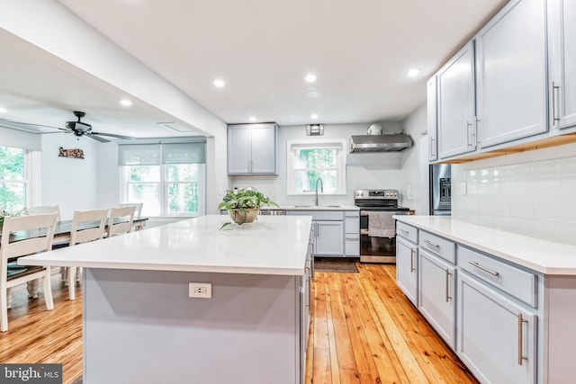 kitchen with light wood-style floors, tasteful backsplash, gray cabinets, and stainless steel range with electric cooktop