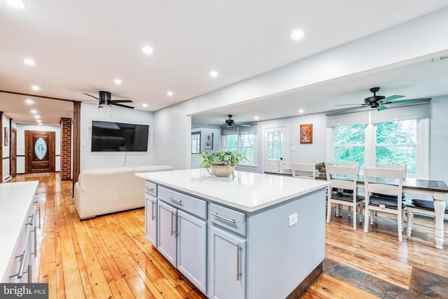 kitchen with light wood-type flooring, recessed lighting, a kitchen island, and gray cabinetry