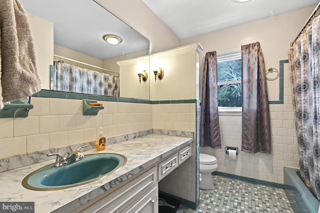 bathroom featuring toilet, vanity, tile patterned flooring, and tile walls