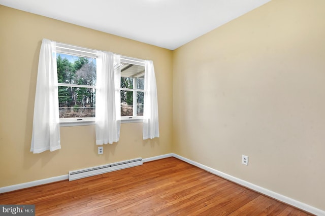 empty room with light wood finished floors, baseboards, and a baseboard heating unit