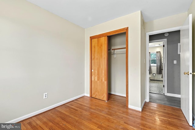 unfurnished bedroom featuring a closet, baseboards, and wood finished floors