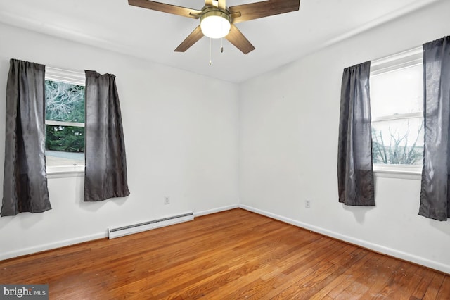 empty room with baseboards, hardwood / wood-style floors, a baseboard radiator, and a healthy amount of sunlight