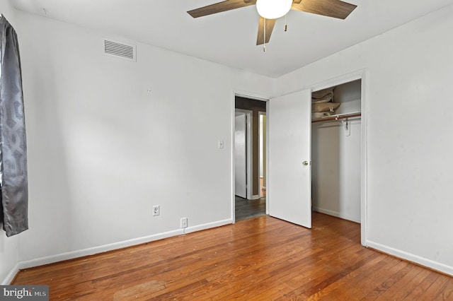 unfurnished bedroom featuring a closet, wood-type flooring, visible vents, ceiling fan, and baseboards