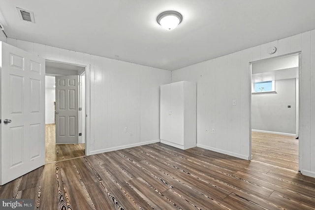 spare room featuring wood finished floors, visible vents, and baseboards