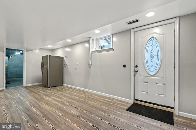 foyer entrance featuring visible vents, baseboards, and wood finished floors