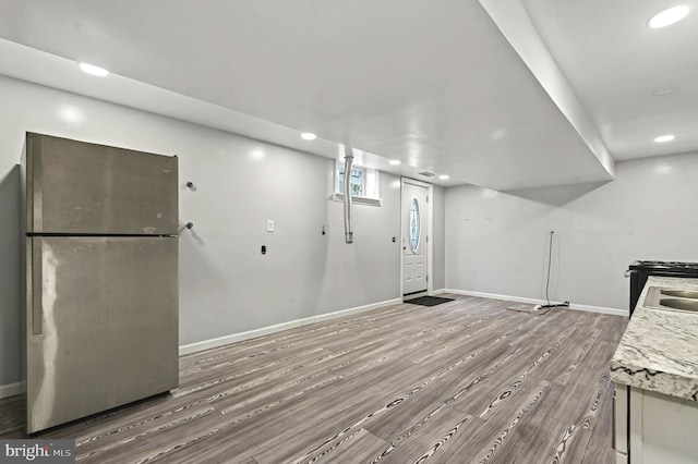 kitchen featuring baseboards, wood finished floors, freestanding refrigerator, light countertops, and recessed lighting