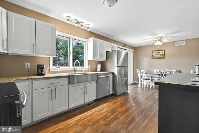 kitchen with dark wood-style floors, stainless steel appliances, ceiling fan, and visible vents