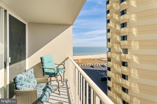 balcony featuring a view of the beach and a water view