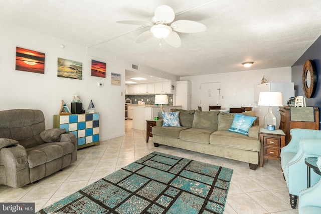 living room with a ceiling fan, visible vents, and light tile patterned floors