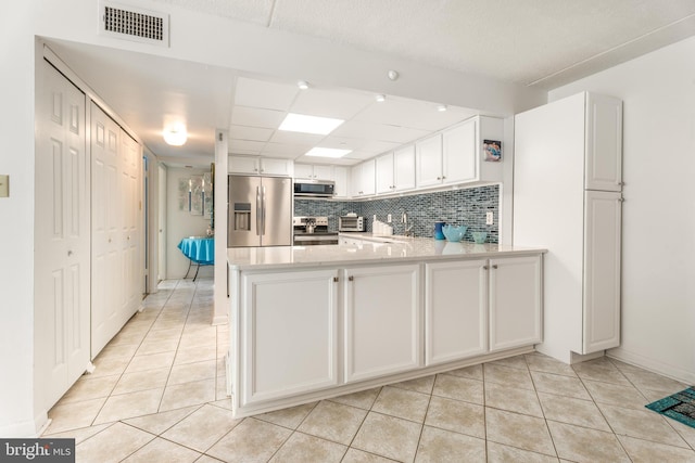 kitchen with visible vents, white cabinets, appliances with stainless steel finishes, backsplash, and light tile patterned flooring