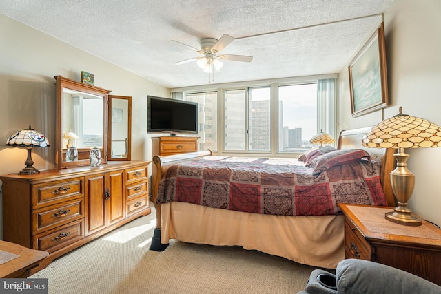 bedroom with a ceiling fan, a textured ceiling, and light colored carpet