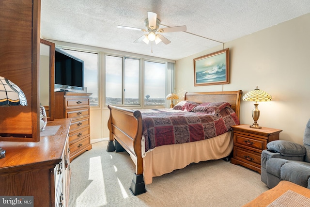 bedroom with a textured ceiling, a ceiling fan, and light colored carpet