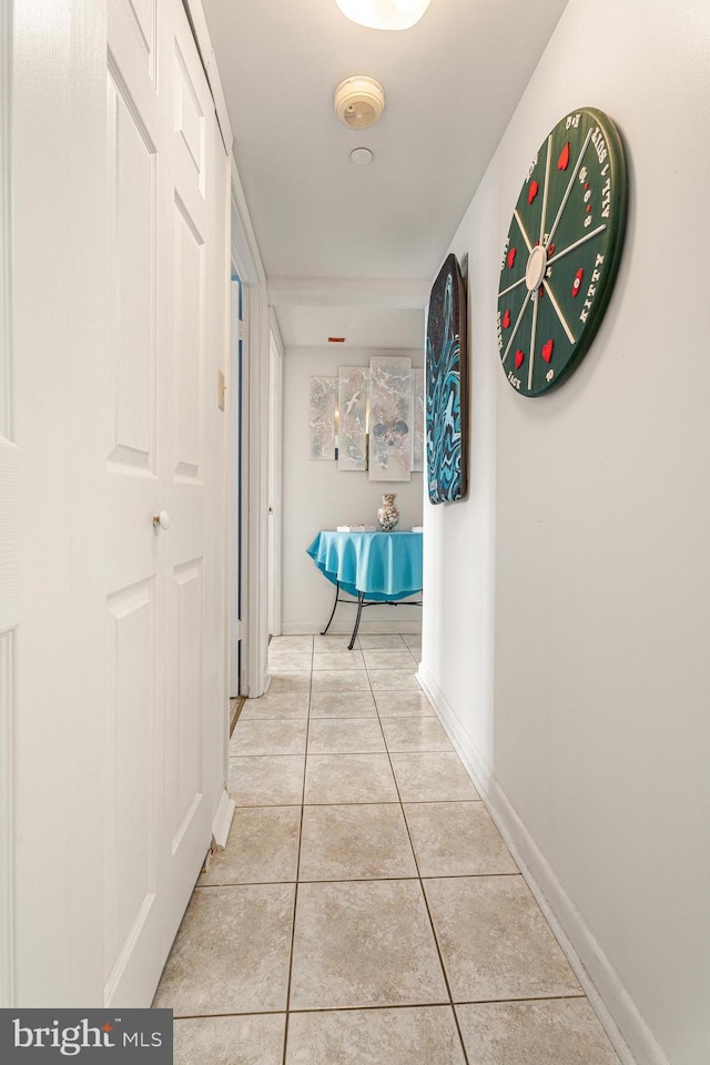 corridor with light tile patterned floors and baseboards