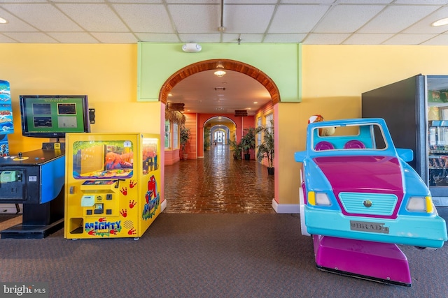 playroom with visible vents, arched walkways, a drop ceiling, and carpet flooring