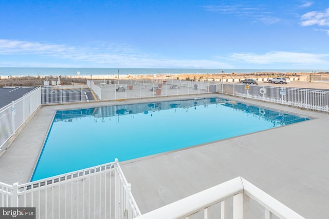 view of swimming pool featuring a water view, fence, a fenced in pool, and a patio