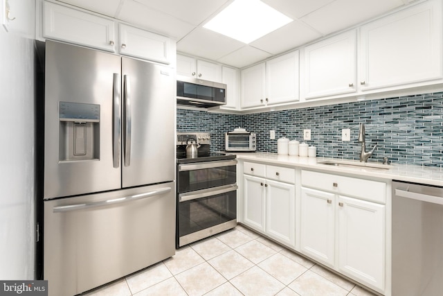 kitchen featuring light tile patterned floors, stainless steel appliances, a sink, light countertops, and tasteful backsplash