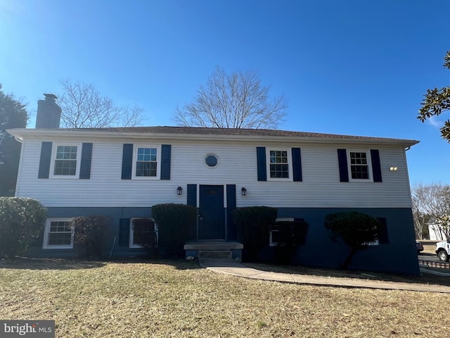 bi-level home with a front yard and a chimney