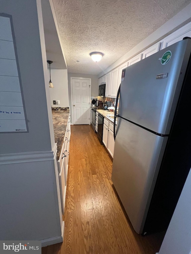 kitchen with a textured ceiling, black appliances, wood finished floors, and white cabinetry