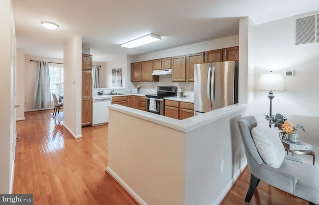 kitchen with under cabinet range hood, a peninsula, visible vents, light wood-style floors, and appliances with stainless steel finishes