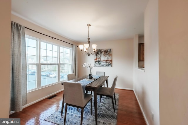 dining room featuring baseboards, visible vents, a chandelier, and hardwood / wood-style floors