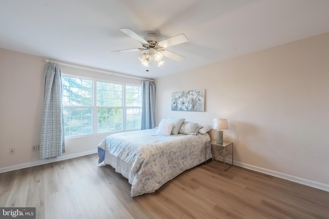 bedroom featuring a ceiling fan, baseboards, and light wood finished floors