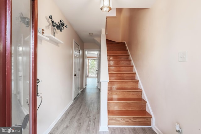 stairway with wood finished floors and baseboards