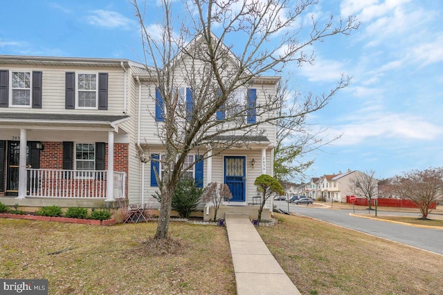 view of front of property with covered porch, a front lawn, and brick siding