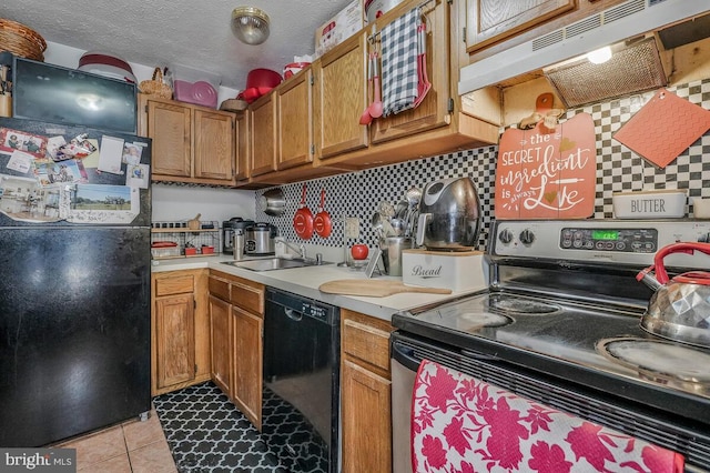 kitchen featuring tasteful backsplash, under cabinet range hood, light countertops, black appliances, and a sink