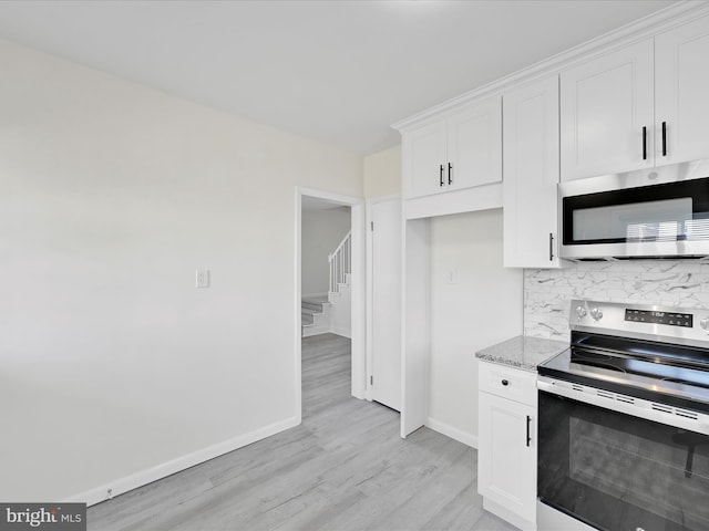 kitchen with white cabinets, decorative backsplash, light wood-style flooring, appliances with stainless steel finishes, and light stone counters