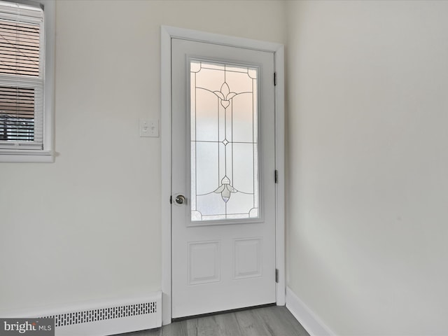 doorway featuring baseboards, baseboard heating, and wood finished floors