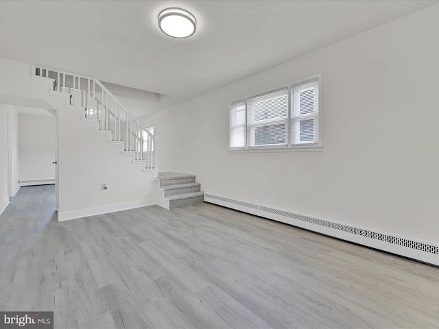 unfurnished living room featuring baseboards, stairs, a baseboard heating unit, and wood finished floors