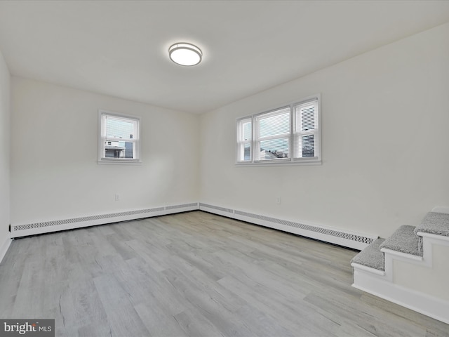 spare room featuring a baseboard radiator, plenty of natural light, and wood finished floors