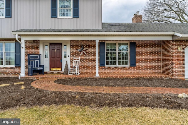 entrance to property with brick siding, a chimney, a shingled roof, and board and batten siding